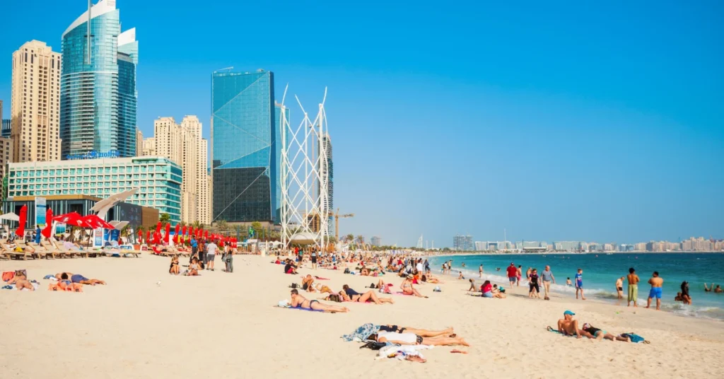 Crowds enjoying JBR Beach Dubai with luxury towers - the lifestyle that awaits UAE residency investors